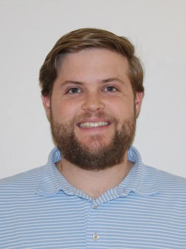 Smiling man with short hair and beard in a light blue striped polo shirt against a plain white background.