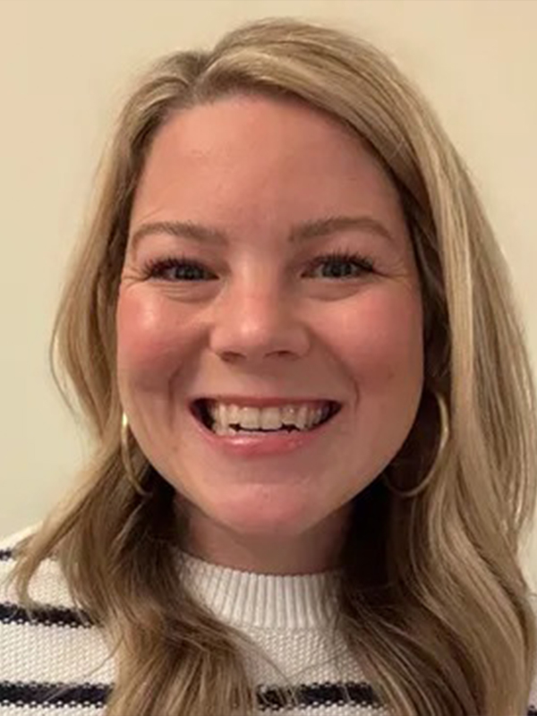 Smiling woman headshot with blonde hair, hoop earrings, and striped sweater on neutral background