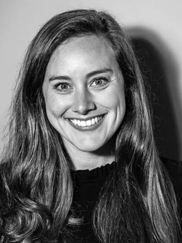 Black-and-white professional portrait headshot of a smiling woman with long hair looking at the camera