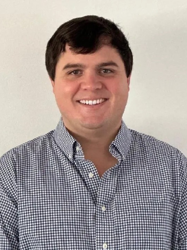 Smiling man in a gingham button-down shirt, professional headshot on a white background