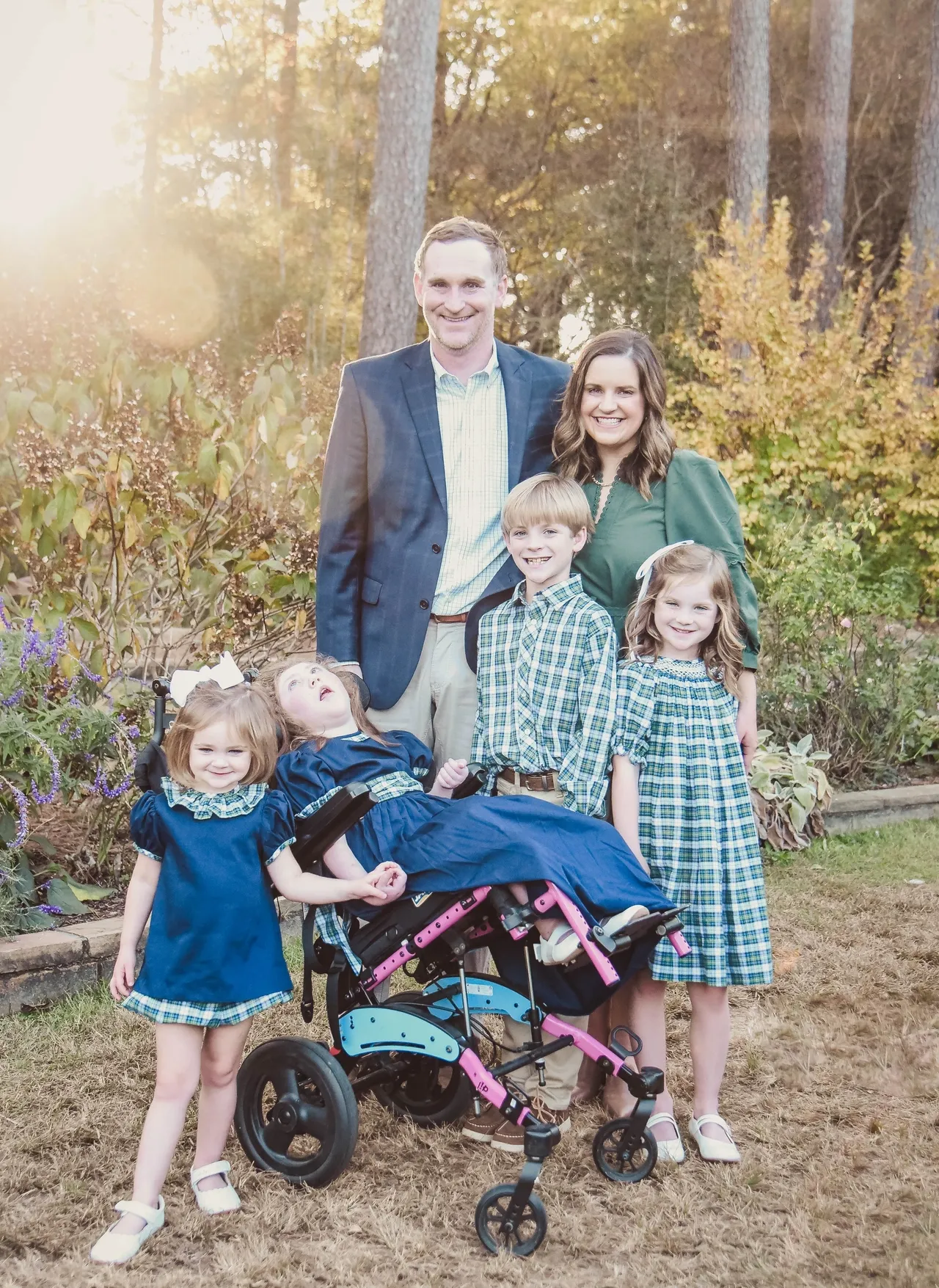 Family photo in a garden at sunset with two parents and four children wearing green and blue outfits
