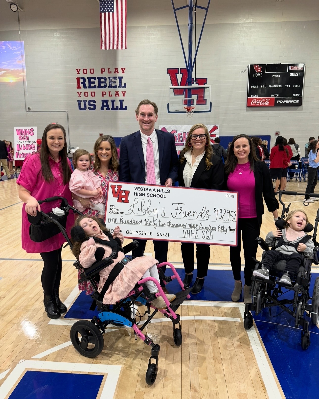 Group at Vestavia Hills High School holds giant check for Libby’s Friends, $132,952, flanked by children in wheelchairs.